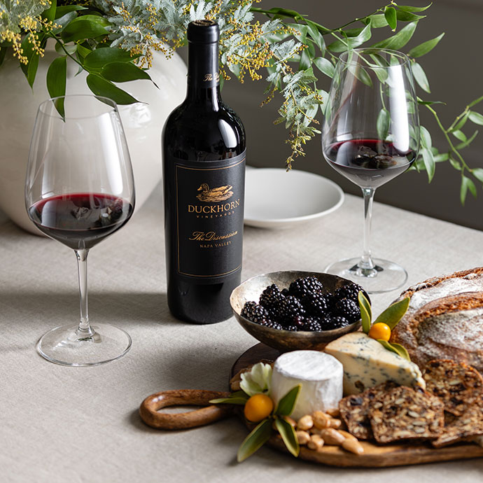 Duckhorn wine bottle on a table next to a cheese board