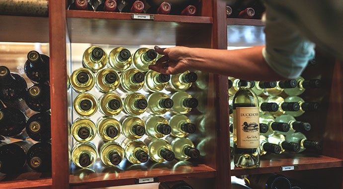Pulling a bottle of Duckhorn wine from a storage rack
