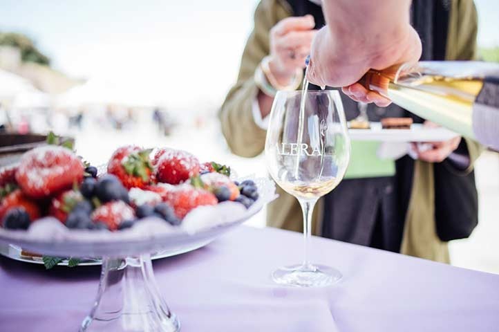 Wine being poured into a glass with a fruit platter